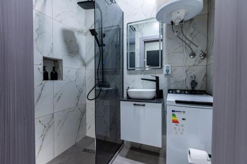 a white bathroom with a shower and a sink at IlieskiApartment in Prilep