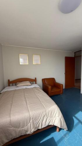 a bedroom with a large bed and a chair at Oasis in Tacna