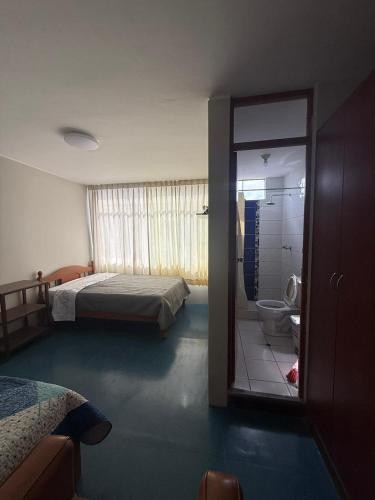 a bedroom with a bed and a bathroom with a toilet at Oasis in Tacna