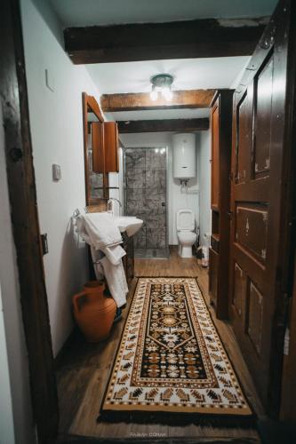a bathroom with a sink and a toilet and a rug at La Romaneasa in Săpânța