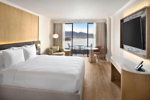 a hotel room with a large bed and a television at Pinnacle Hotel Harbourfront in Vancouver