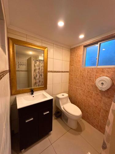 a bathroom with a toilet and a sink and a mirror at NurHome in Mejillones