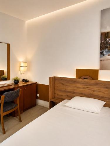 a bedroom with a bed and a desk and a chair at The Square Central Prishtina in Prishtinë