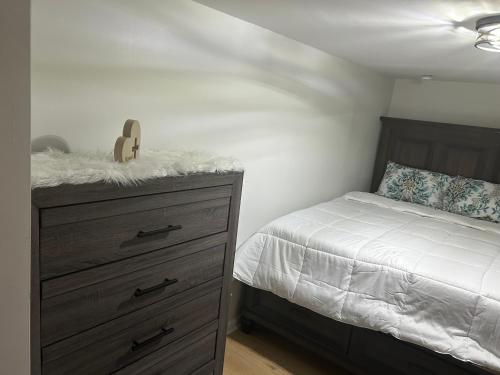 a bedroom with a bed and a dresser with a white bedspread at Private basement apartment with separate entrance in Yonkers