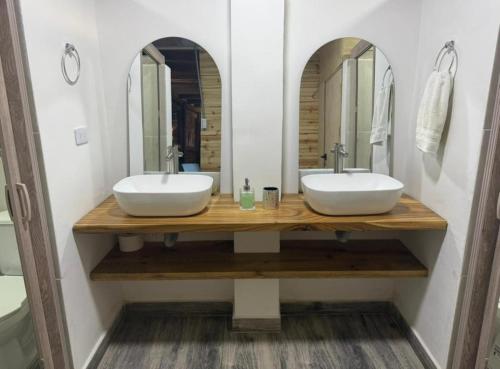 a bathroom with two sinks and two mirrors at Cabaña Vivanco in Coveñitas