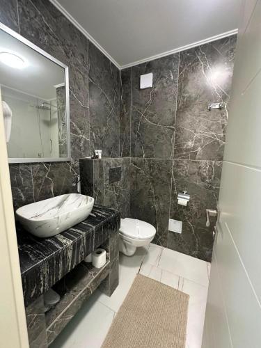a bathroom with a sink and a toilet and a mirror at Marevento Hotel in Costinesti