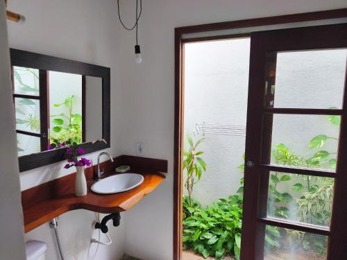 a bathroom with a sink and a mirror and a window at Dona Maragô Pousada in Maragogi