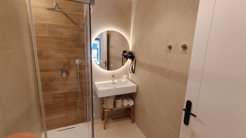 a bathroom with a sink and a shower with a mirror at Hostal Manel in Pineda de Mar