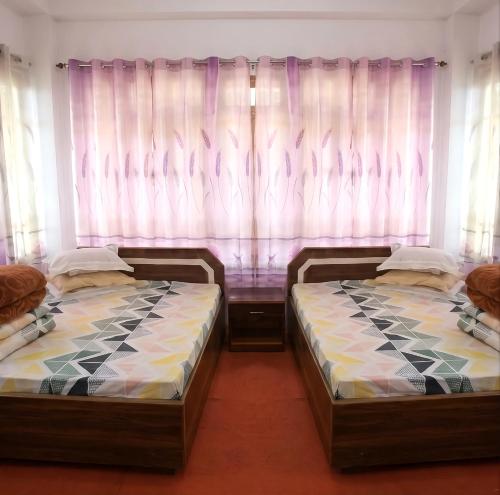 two beds in a room with windows with curtains at Ningma Lamu Homestay in Mangpu
