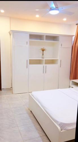 a white bedroom with a bed and white cabinets at takara stay in Delmas