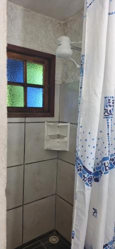 a bathroom with a window and a curtain in it at Pousada Tia Lucia in Saquarema