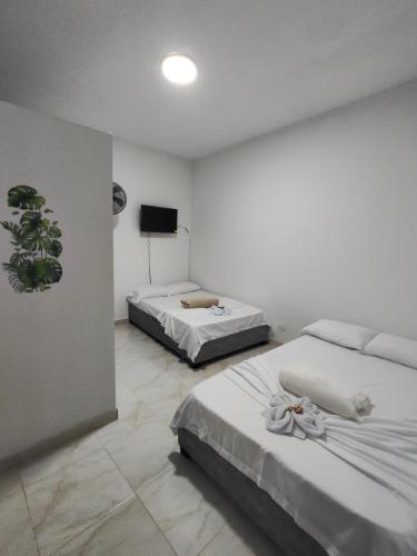 a bedroom with two beds and a television in it at Hospedaje Monasterio in Buga