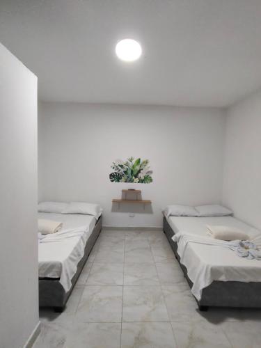 a room with three beds and a potted plant at Hospedaje Monasterio in Buga