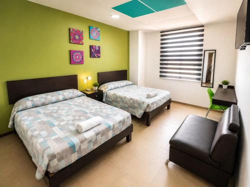 una camera da letto con due letti, una sedia e un divano di Hotel Plazha Express a Tuxtla Gutiérrez