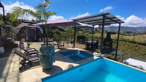 a pool with chairs and an umbrella next to a house at Hotel Deluxe Glamping in Guatapé