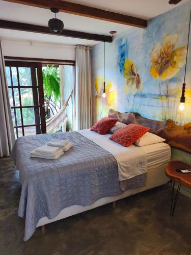 a bedroom with a large bed with a painting on the wall at Dona Maragô Pousada in Maragogi