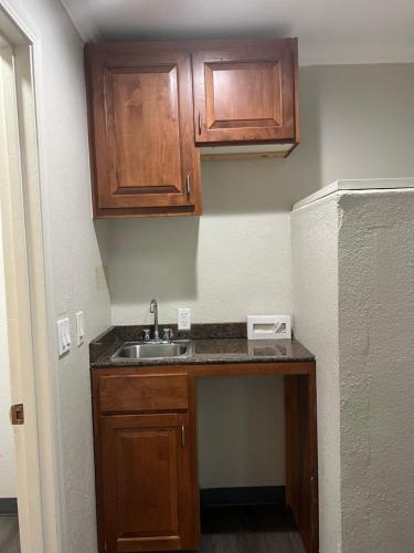 a small kitchen with a sink and wooden cabinets at Golden Eagle Motel in Dorris