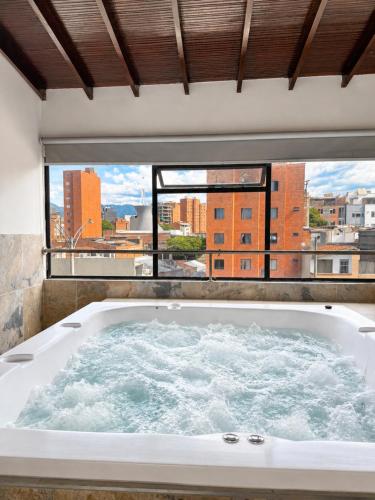 a bath tub in a room with a large window at Hotel Ofix - Laureles in Medellín