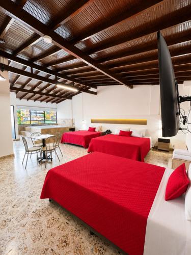 a room with three beds and a table and chairs at Hotel Ofix - Laureles in Medellín