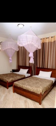 two beds in a bedroom with pink chandeliers at Meraki Palate in Entebbe