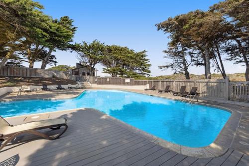 a swimming pool with lounge chairs on a wooden deck at Rita's-by-the-Sea in Moss Landing