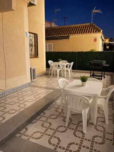 a patio with white tables and chairs on a patio at Verdi House in Torrevieja
