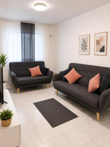 a living room with two black couches and a tv at Verdi House in Torrevieja