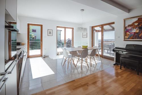 a kitchen and dining room with a table and a piano at Piran Panorama Pool Villa in Piran