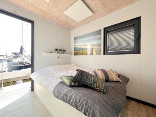 a bedroom with a bed with a large window at Jopies Houseboat in Maasbommel