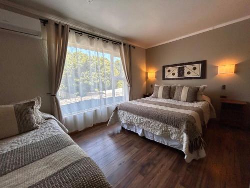 a bedroom with two beds and a large window at Hostal Lago Ranco Boutique in Lago Ranco