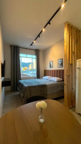 a hotel room with two beds and a table with a flower on it at Studio no Centro com VISTA PARA O CRISTO in Poços de Caldas
