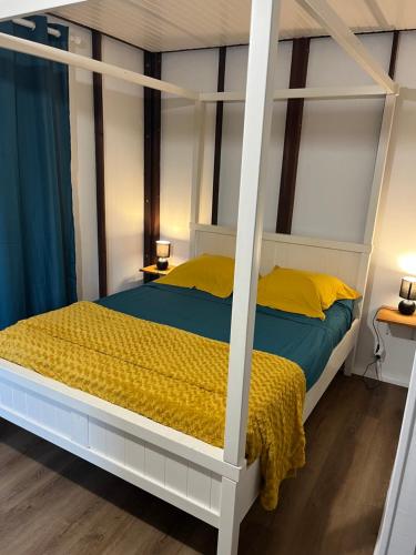 a bedroom with a canopy bed with yellow pillows at an eol caraibes in Trois-Rivières