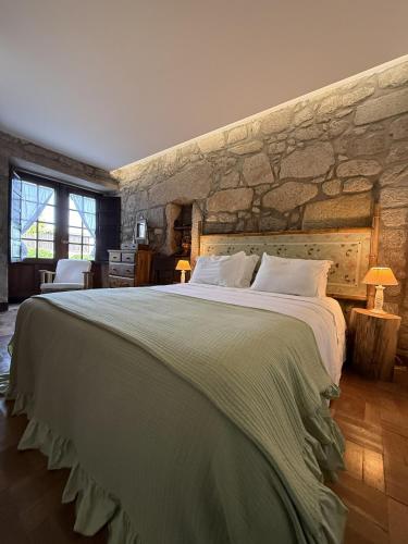 a bedroom with a large bed with a stone wall at Paco d'Anha in Viana do Castelo