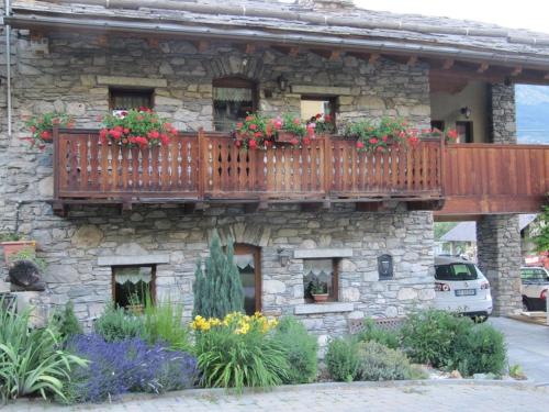 un edificio in pietra con balcone fiorito di Appartamento Le Jardin CIR VDA Aymavilles 0009 ad Aymavilles