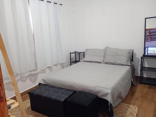 a bedroom with a bed with a black ottoman and a window at Recanto Eucaliptos in Araçoiaba da Serra