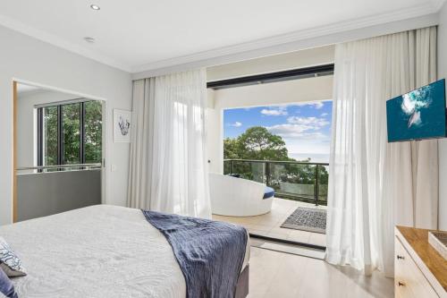 a bedroom with a bed and a tub and a balcony at Villa Mariposa in Coolum Beach