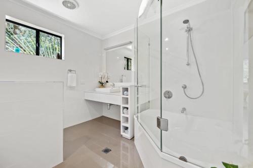 a white bathroom with a shower and a sink at Villa Mariposa in Coolum Beach