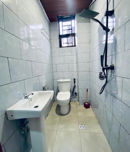 a white bathroom with a toilet and a sink at basalt&bamboo B&B in Ruhengeri