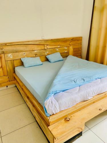 a wooden bed with two blue pillows on it at basalt&bamboo B&B in Ruhengeri