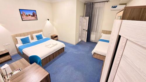 a hotel room with two beds and a desk at Premium Yunusobod Hotel in Darkhon