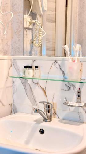 a bathroom sink with a glass shelf above it at Premium Yunusobod Hotel in Darkhon