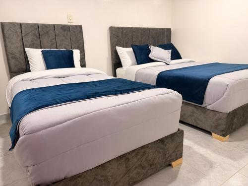 two beds with blue and white sheets in a room at Hotel Hostal Urban18 in Bogotá