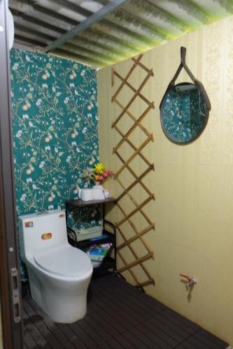 a bathroom with a toilet and a wall at The Bare Nest Retreat - Xóm Đung Homestay in Hòa Bình
