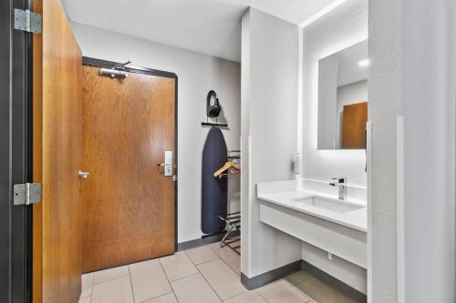 a bathroom with a sink and a wooden door at Quality Inn Sheridan in Sheridan