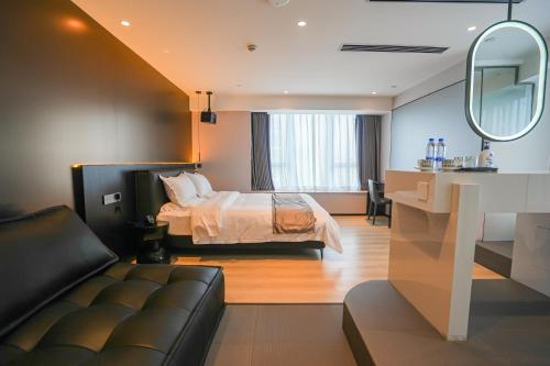 a bedroom with a bed and a couch and a mirror at Modern Space Hotel--Guangzhou Nansha Wanda Plaza in Guangzhou