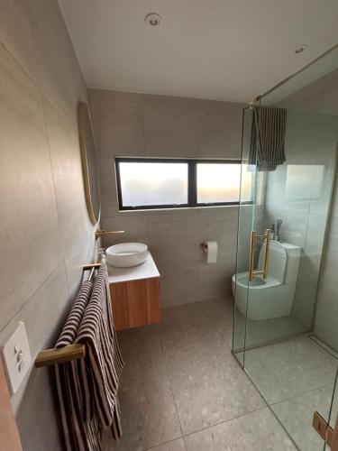 a bathroom with a sink and a toilet and a shower at Cooks Beach Studio Escape in Cooks Beach