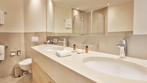ein Badezimmer mit zwei Waschbecken, einem WC und einem Spiegel in der Unterkunft Hotel TheGreen ehemals Köln11 in Köln