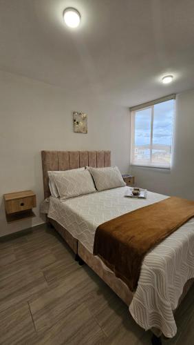 a bedroom with a large bed with a window at Apartamento Urban Paipa in Paipa