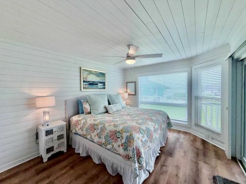 a bedroom with a bed and two windows at Sandy Beach Retreat and Gulf View in Galveston