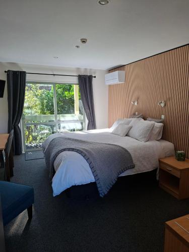 a bedroom with a large bed and a window at La Rochelle Motel in Akaroa